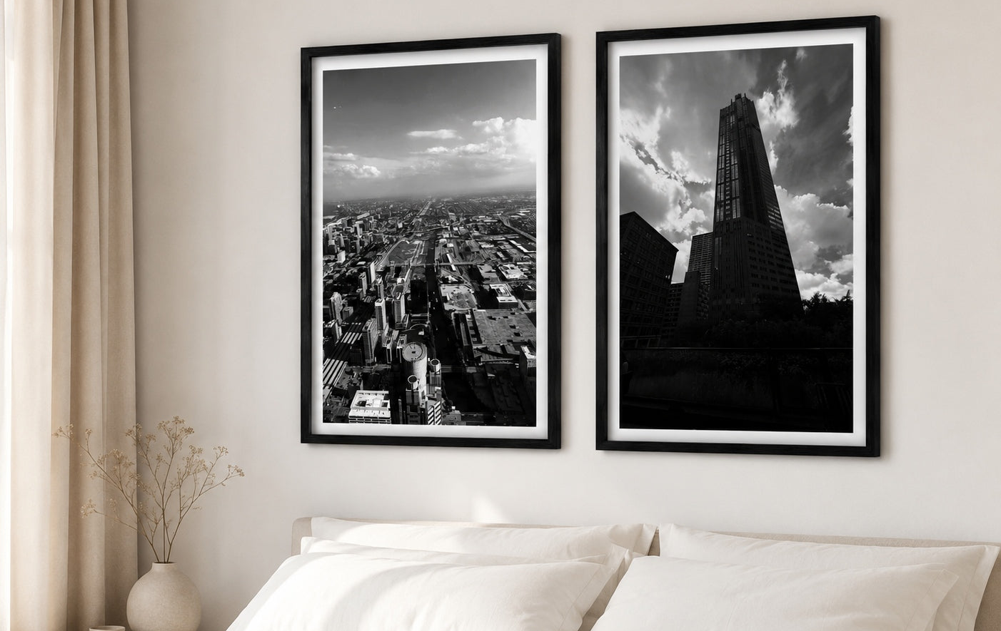 Two framed black and white cityscape prints on a wall above a bed.